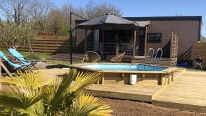 eine Terrasse mit Pool und Sonnenschirm in der Unterkunft Cottage du garlai in Bressuire