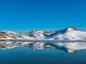 un reflet des montagnes enneigées dans un lac dans l'établissement Apartments center Zorić, à Žabljak