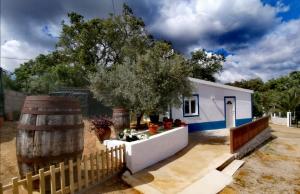 Casa blanca con valla de madera y barril en Monte da Vinha Nova, en Santiago do Cacém