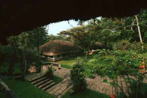 een huis met een rieten dak in een tuin bij Spice Village Thekkady - a CGH Earth Experience in Thekkady