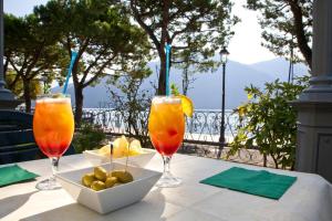 einen Tisch mit zwei Gläsern Saft und einer Schale Obst in der Unterkunft Hotel Lenno in Lenno