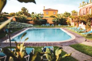 una piscina in un cortile con sedie e un edificio di Hotel Pinomar a El Puerto de Santa María