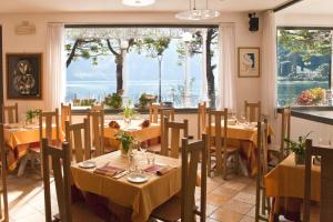 ein Restaurant mit Tischen und Stühlen und einem großen Fenster in der Unterkunft Hotel Lenno in Lenno