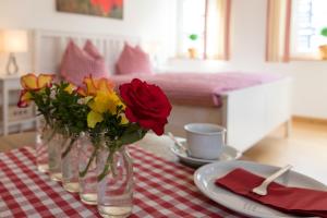 une table avec des vases de fleurs sur un tissu de table rouge et blanc dans l'établissement Feldmann-Schütte, à Schmallenberg