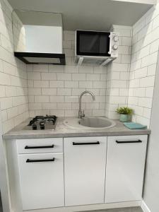 a white kitchen with a sink and a microwave at Tiffany Apartment in Irpin'