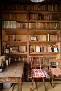 een bibliotheek met een houten tafel, een stoel en boeken bij 旧鈴木邸 女性専用 in Matsuyama