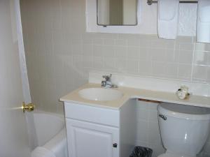 a bathroom with a sink and a toilet and a mirror at Mecca Motel in Colorado Springs