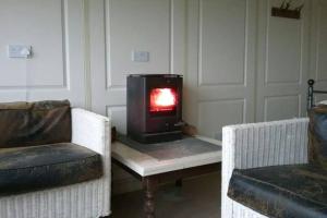 ein Wohnzimmer mit einem Herd auf einem Tisch mit 2 Stühlen in der Unterkunft Stags View,Unique eco cabin, Dartmoor views in South Brent