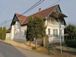 a white house with a brown roof and a tree at Viola Apartmanház in Bogács