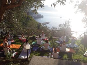 Un gruppo di persone sedute sull'erba a fare yoga di Villa Rina ad Amalfi