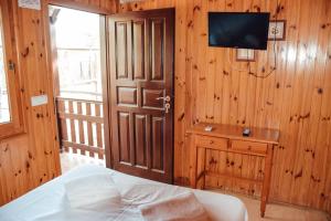 - une chambre avec un lit et une télévision sur un mur en bois dans l'établissement Camping La Aldea, à El Rocío