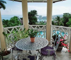 uma mesa e cadeiras num alpendre com vista para o oceano em Blue Topaz em Ocho Rios