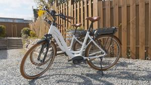 uma bicicleta branca estacionada ao lado de uma cerca em Nordsee-Hotel Hinrichsen em Husum