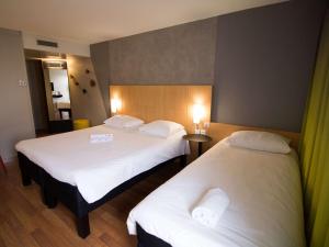 Cette chambre d'hôtel comprend 2 lits avec des draps blancs. dans l'établissement ibis Rennes Beaulieu, à Cesson-Sévigné