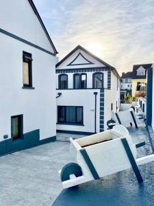 a patio with two white chairs and a house at Feeney's Audubon Lodge in Galway