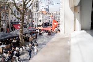 Cette chambre offre une vue sur une rue de la ville avec des personnes et des cafés. dans l'établissement Ginny's studio op de Grote Markt, à Breda