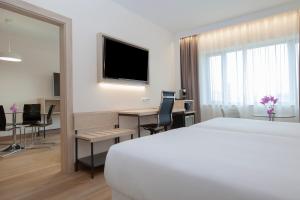 una camera d'albergo con letto, scrivania e TV di Hotel Puerta de Bilbao a Barakaldo