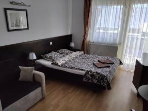 um pequeno quarto com uma cama e um sofá em Willa Latarnik - doskonała lokalizacja, blisko atrakcji, 20min do plaży em Łeba