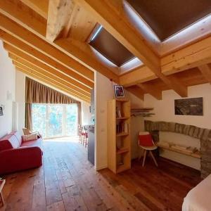 uma sala de estar com tectos em madeira e um sofá vermelho em Foresteria B&B Vecchiascuola Pianazzola em Chiavenna