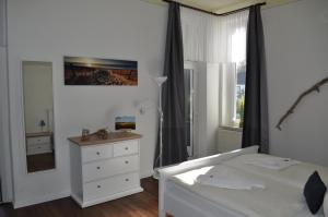 een slaapkamer met een bed, een dressoir en een raam bij Pension Villa Frohsinn Sellin auf Rügen in Ostseebad Sellin