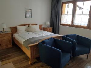 ein Schlafzimmer mit einem Bett und zwei blauen Stühlen in der Unterkunft Hotel Beau-Séjour in Leukerbad