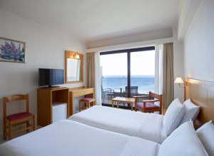 een hotelkamer met een bed en uitzicht op de oceaan bij Cactus Hotel in Rhodos-stad