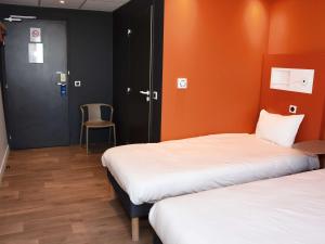 2 Betten in einem Zimmer mit orangefarbenen Wänden und einem Stuhl in der Unterkunft ibis budget Langres in Langres