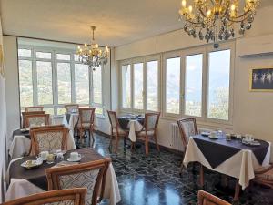 una sala da pranzo con tavoli, sedie e finestre di Hotel Villa Margherita a Limone sul Garda