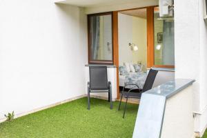 eine Terrasse mit Gras, 2 Stühlen und einem Sofa in der Unterkunft Tündérkert Hotel Noszvaj in Noszvaj