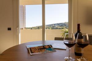 uma mesa com uma garrafa de vinho e dois copos em Istai Poetto Apartment em Cagliari