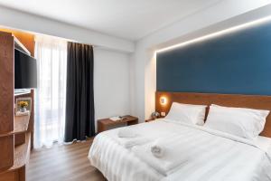 een slaapkamer met een groot wit bed en handdoeken bij DAYS City Suites in Patra