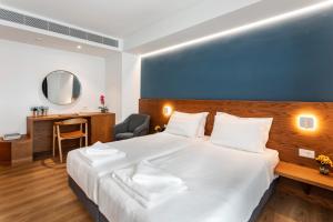 een hotelkamer met een groot wit bed en een bureau bij DAYS City Suites in Patra