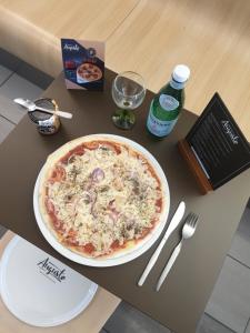 uma pizza sentada em cima de uma mesa com um prato em B&B HOTEL Lyon Vénissieux em Vénissieux