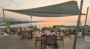 un restaurante con mesas y sillas en una terraza en Crowne Plaza Muscat, an IHG Hotel, en Mascate