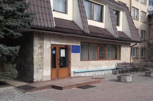 a building with a wooden door and a wooden bench at Prykarpattya in Ivano-Frankivsʼk