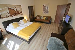 a bedroom with a large bed and a couch at Gellény Lux Apartman in Gyula