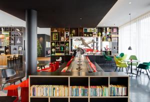 une bibliothèque avec une table, des livres et des chaises dans l'établissement citizenM Paris Charles de Gaulle Airport, à Roissy-en-France