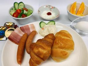 a plate of food with sausage and croissants and salad at Smile Hotel Nagoya Sakae in Nagoya