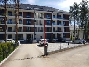 un gran edificio con coches estacionados en un estacionamiento en SunStone Apartment, en Zlatibor