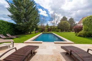 een zwembad met twee banken naast een tuin bij Hôtel Le Clos in Montagny-lès-Beaune