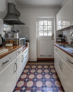 - une cuisine avec des placards blancs et un sol coloré dans l'établissement Cranborne House, à Poole