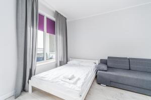 Habitación blanca con cama y sofá en Apartamenty Proeko Polonia, en Kołobrzeg