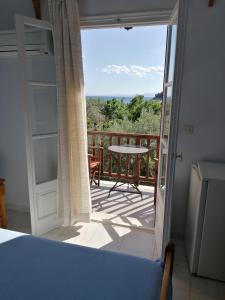 una camera da letto con vista su un balcone con tavolo di Limnonari Beach Rooms a Skopelos Town