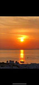 een zonsondergang over de oceaan met een boot in het water bij Ibiscus Boutique in Mykonos-stad