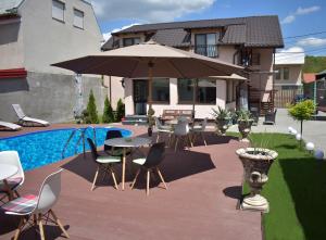 d'une terrasse avec des tables, des chaises et un parasol. dans l'établissement Pensiunea Casa Zece, à Turda