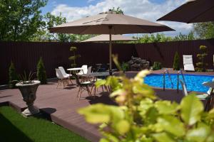 une terrasse avec une table, un parasol et une piscine dans l'établissement Pensiunea Casa Zece, à Turda