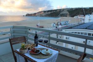 - une table avec une assiette de nourriture et de vin sur un balcon dans l'établissement Beachfront Apartment Nazaré, à Nazaré