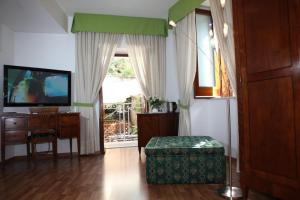 un soggiorno con TV, sedia e tavolo di La Magnolia Sorrento - City Centre Hotel a Sorrento