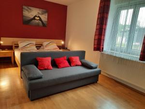 a bedroom with a couch and a bed with red pillows at Gästehaus Ranftl in Unterlamm