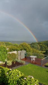 a rainbow in the sky over a deck with a table at Gîte du Soleil in Anhée